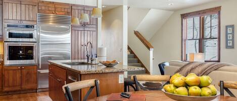 A modern kitchen with wooden cabinets, stainless steel appliances, and a dining area with a table set for two.