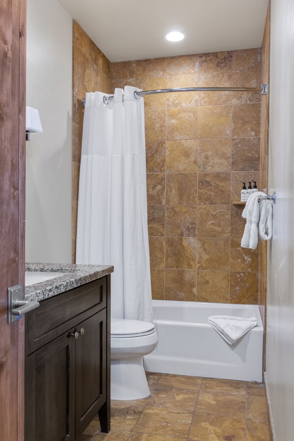 A bathroom with a toilet, bathtub, and shower curtain. - Outpost: Love Ridge 251 - Spacious, Air Conditioned (Jackson)