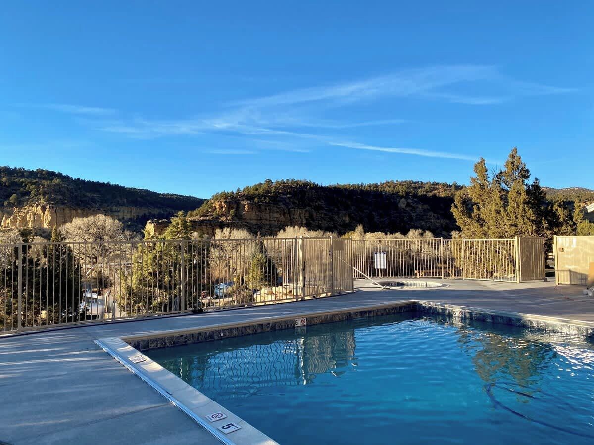 A swimming pool with a view of a mountainous landscape, surrounded by a fence.