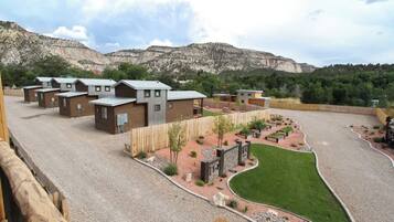 A residential area with multiple houses, a landscaped garden, and a mountainous backdrop.