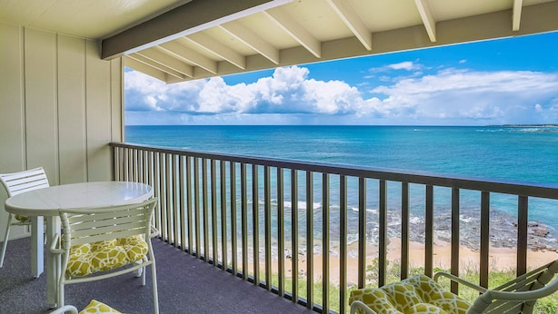 Een balkon met uitzicht op zee, een tafel en twee stoelen.