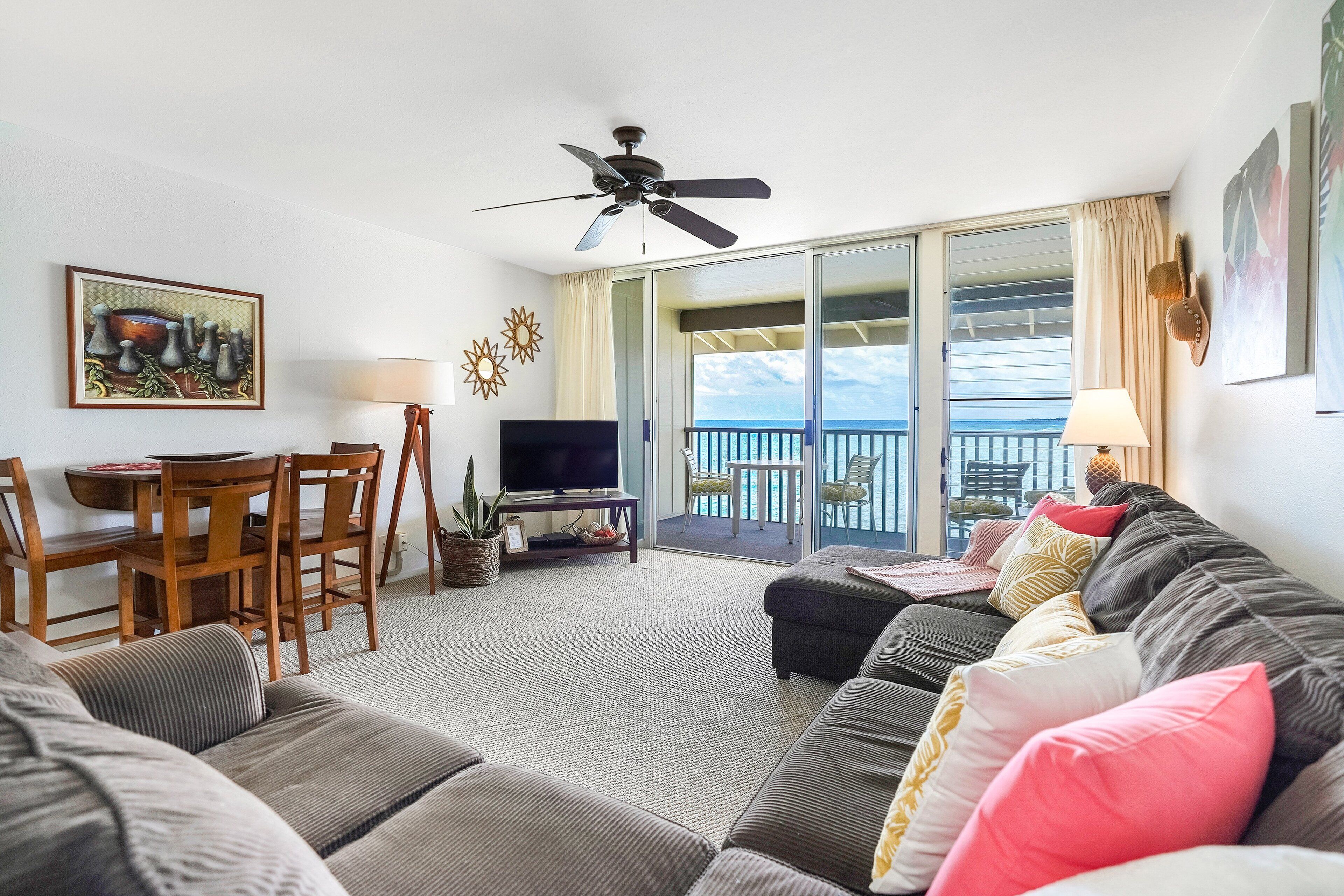 Un salon comprenant un canapé, un téléviseur, une table à manger, des chaises et un balcon avec vue.