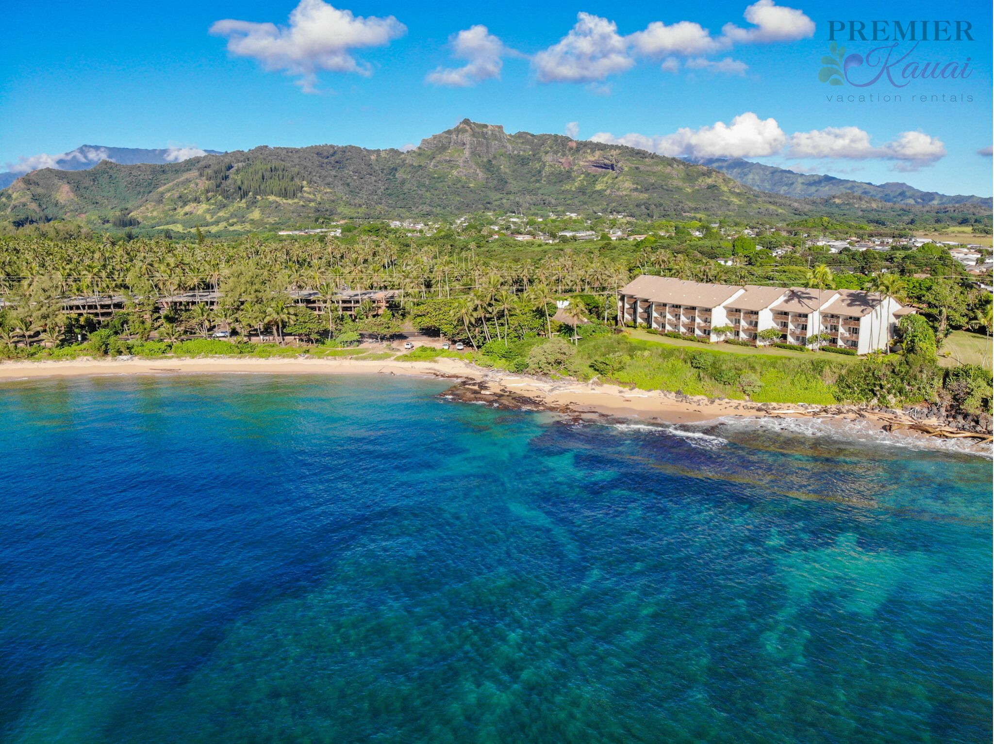 A coastal resort with beachfront villas, clear blue waters, and lush greenery.