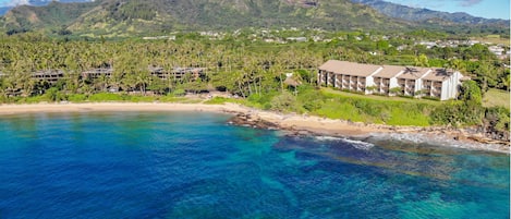 A coastal resort with beachfront villas, clear blue waters, and lush greenery.