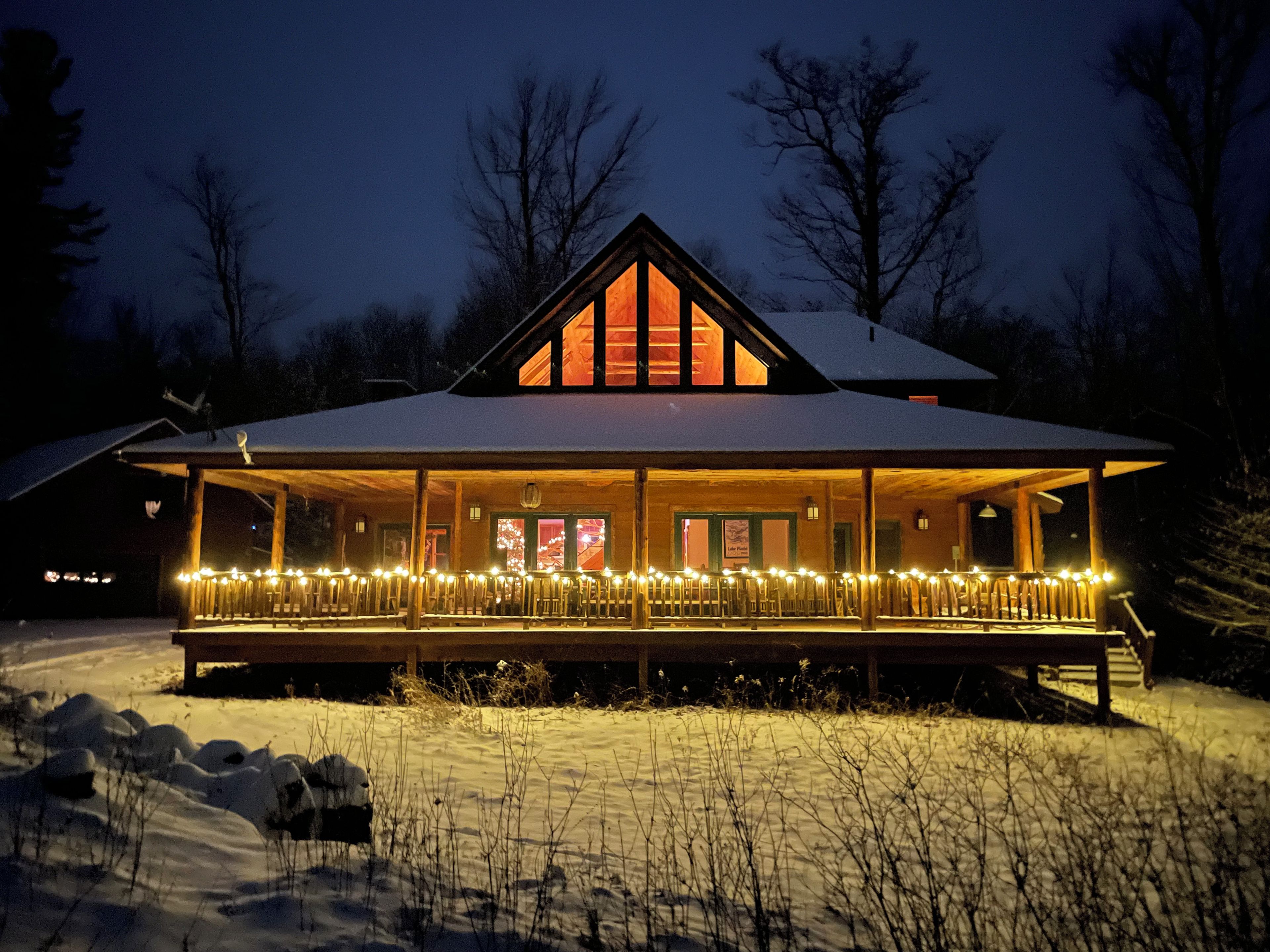 Eine Lodge mit überdachter Veranda, verschneitem Gelände und Holzfassade.