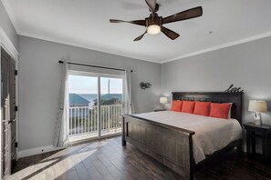 Un dormitorio con cama, mesita de noche, ventilador de techo y vistas por una puerta corredera.