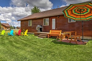 Eine Holzhütte mit einer Terrassenfläche, Sitzgelegenheiten im Freien und einem Grill.