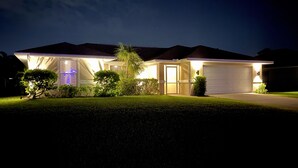 A residential house at night with a well-lit garage and front yard. - Modern 3 bedroom, 2 bath getaway with HEATED private pool and jacuzzi (Fort Myers)