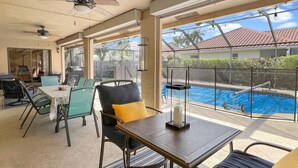 A covered patio area with a pool, outdoor seating, and a ceiling fan.