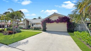 A single-story house with a garage, surrounded by a well-maintained lawn and various plants.
