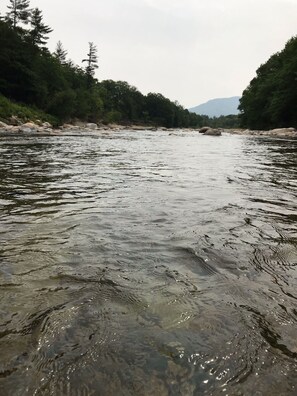 Une rivière aux eaux claires, bordée d’arbres et de rochers.