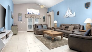 A living room with a brown leather sofa, a wooden coffee table, and a TV on a stand. - Fairytale Villa - 2 Masters, Privacy Fence! (Kissimmee)