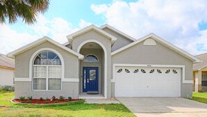 A single-story house with a blue front door, a garage, and a well-maintained lawn. - Fairytale Villa - 2 Masters, Privacy Fence! (Kissimmee)