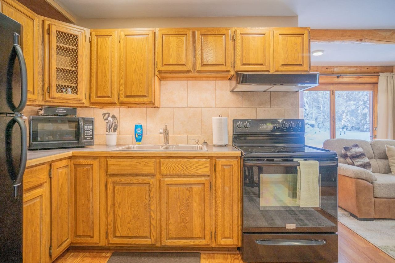 Une cuisine avec des meubles de rangement en bois, un four à micro-ondes, une cuisinière et un évier.