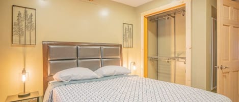 Ein Schlafzimmer mit einem Bett, Nachttischlampen, einem Holzbalken an der Decke und einer Tür.
