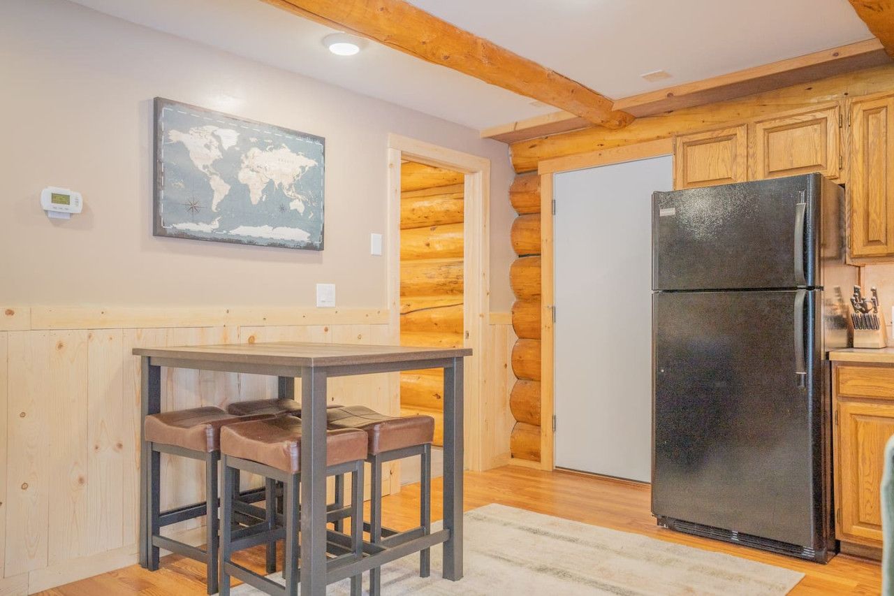 A kitchen with a wooden interior, a black refrigerator, and a world map on the wall.