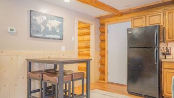 A kitchen with a wooden interior, a black refrigerator, and a world map on the wall.