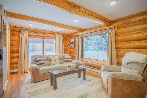 A cozy log cabin interior with a sofa, armchair, and a coffee table.