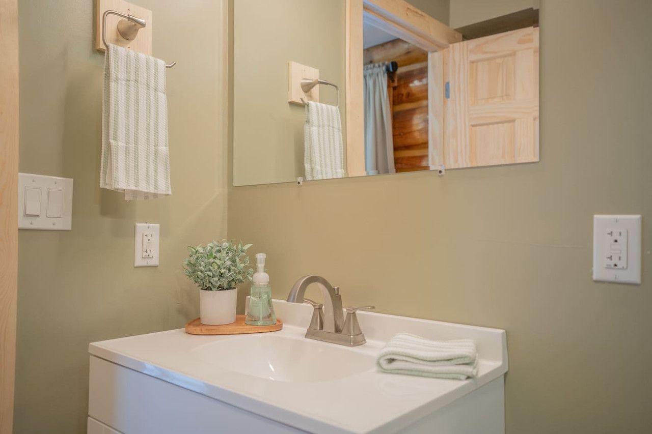 A bathroom with a white sink, a mirror, and a towel rack.