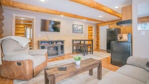 A log cabin interior with a living room, kitchen, and dining area. - Tucked Away Timber Lower Suite (Fairbanks)