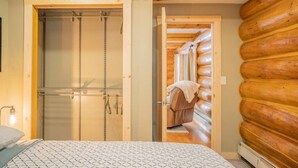 Een slaapkamer met een bed, een houten deur en uitzicht op een blokhut.