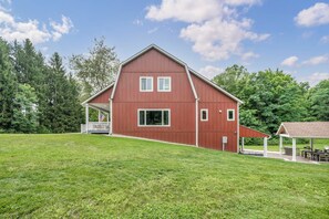 A red barn with a porch and a covered patio area.