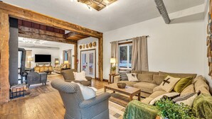 Una sala de estar acogedora con chimenea, vigas de madera y televisor.