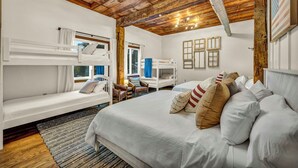Una habitación con literas, una cama grande y techo de madera.