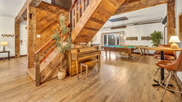 Una habitación amplia con una escalera de madera, mesa de billar y mesa de futbolín.