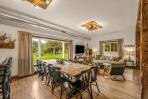 A spacious living area with a dining table, chairs, a sofa, and a TV.
