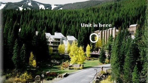 A residential area with a road, houses, and dense forest. A sign indicates a unit is here. - Ski-in Ski-Out:King in Master; Quiet End Unit; high speed secure internet (Winter Park)