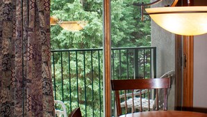 A dining area with a wooden table, chairs, and a view of greenery through a glass door. - Ski-in Ski-Out:King in Master; Quiet End Unit; high speed secure internet (Winter Park)