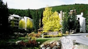 A resort with modern buildings, a stone wall, and a variety of trees including a prominent yellow one. - Ski-in Ski-Out:King in Master; Quiet End Unit; high speed secure internet (Winter Park)