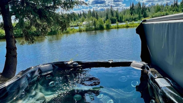 A hot tub with a clear view of a lake and forest in the background.