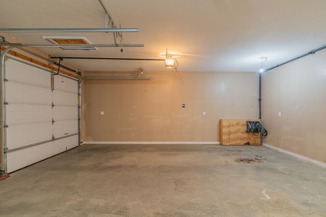 Eine Garage mit Betonboden, einer weißen Garagentür und einer Holzkiste rechts.