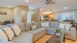 A modern living room with a sectional sofa, wooden coffee table, and a ceiling fan.