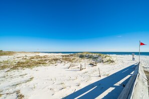 A sandy beach with a wooden boardwalk and a red flag. - Escape to the Beach! Phoenix 8, 1402, 2 BR/2 Bath (Orange Beach)