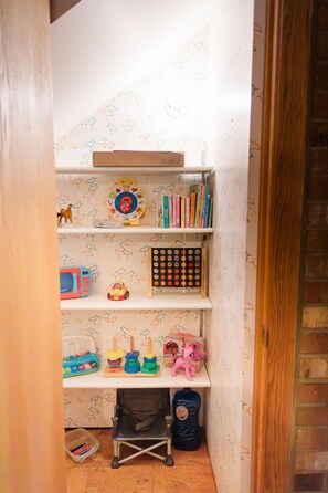 Ein Kinderspielzimmer mit Bücherregal, Spielzeug und kleinem Schreibtisch.