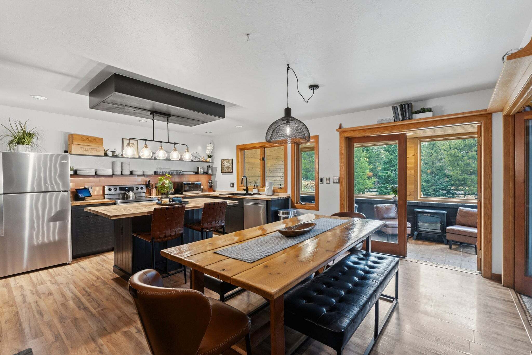 Una cocina moderna con una isla central, una mesa de comedor de madera y asientos.