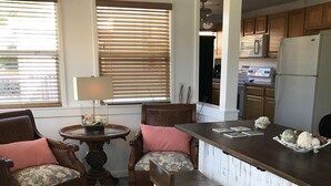 A kitchen with wooden cabinets, a refrigerator, and a dining area with a bar stool and two chairs.