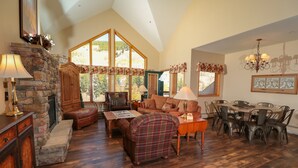 A spacious living room with a stone fireplace, large windows, a dining area, and a chandelier. - 4BR4BA Keystone Condo Rental, Walk to Lifts.. GreatRentalKeystone in The Gateway (Keystone)