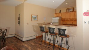 A kitchen with wooden cabinets, a refrigerator, and a bar area with stools. - 4BR4BA Keystone Condo Rental, Walk to Lifts.. GreatRentalKeystone in The Gateway (Keystone)