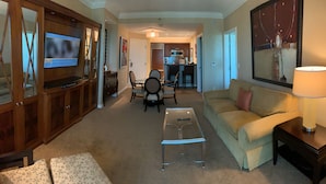 Ein Wohnzimmer mit Sofa, Couchtisch, Fernseher und Essbereich mit Stühlen und Tisch.