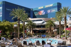 Et hotel med stort poolområde, palmer og et tydeligt MGM Grand skilt.
