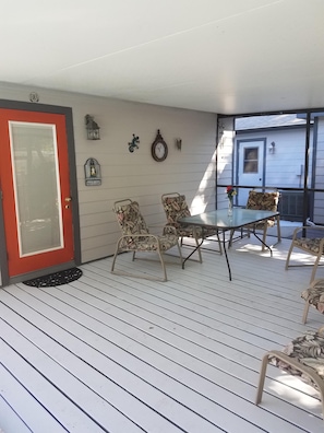 Un patio techado con mesa y sillas, una puerta y decoración mural.