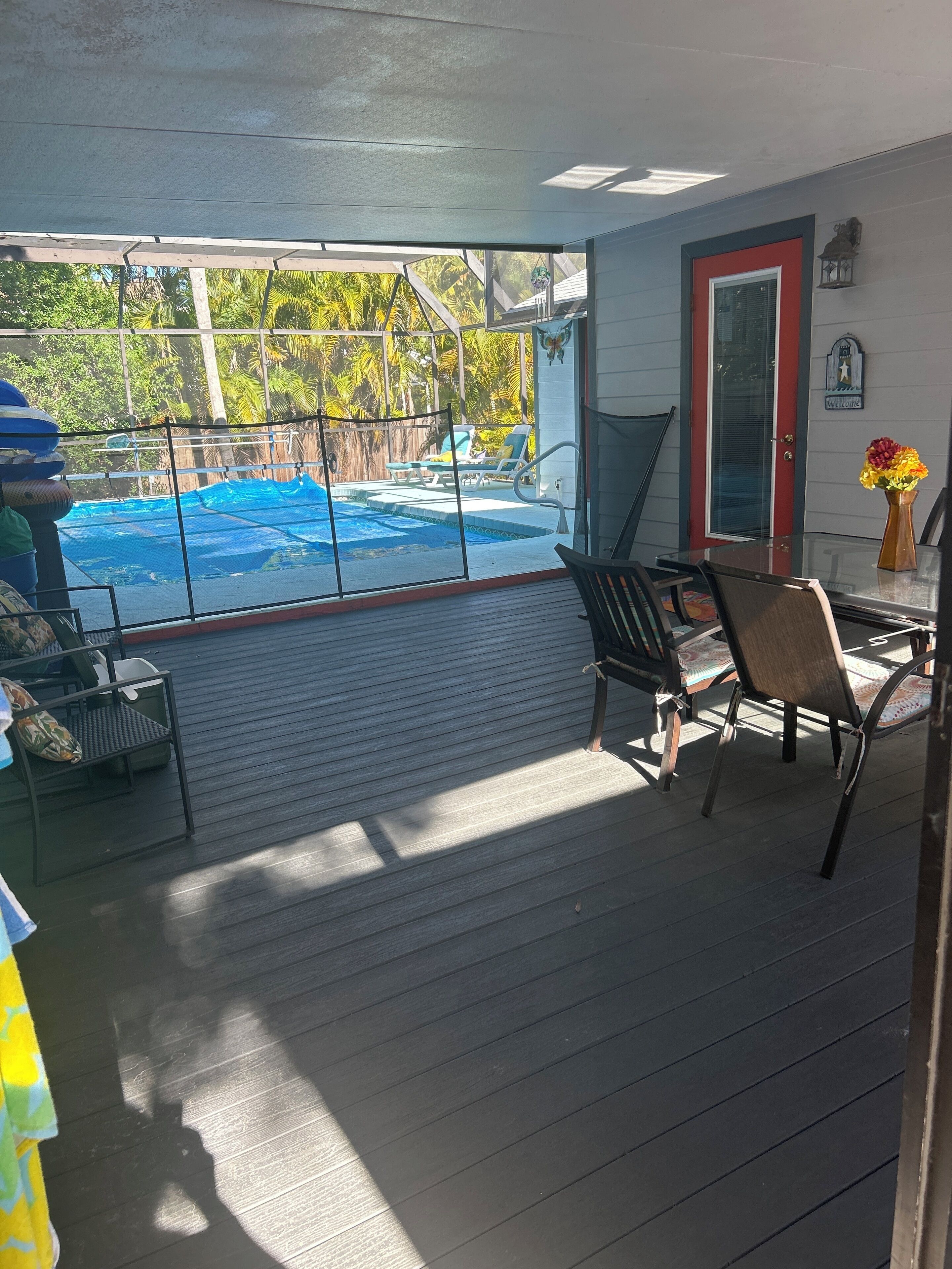 Ein überdachter Außenbereich mit Pool, Stühlen und einem Tisch.