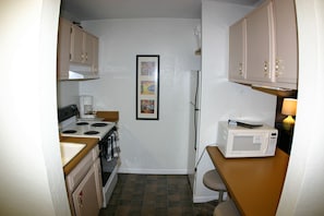 Una cocina compacta con estufa, microondas y refrigerador.