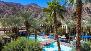 A pool area with palm trees, lounge chairs, and a mountain backdrop. - Legacy Villas private villa w/ view- steps to pool- bikes & arcade game included (La Quinta)