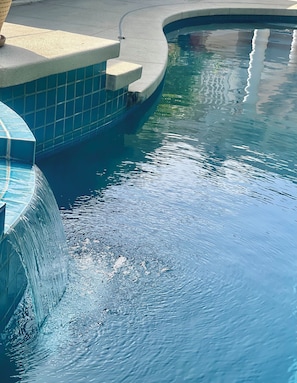 A swimming pool with a clear water feature and a tiled edge.