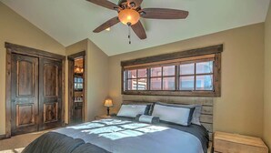 A bedroom with a large bed, a ceiling fan, a window, and wooden doors. - Minutes from World Class Ski Resorts, Hot Tub! (Silverthorne)